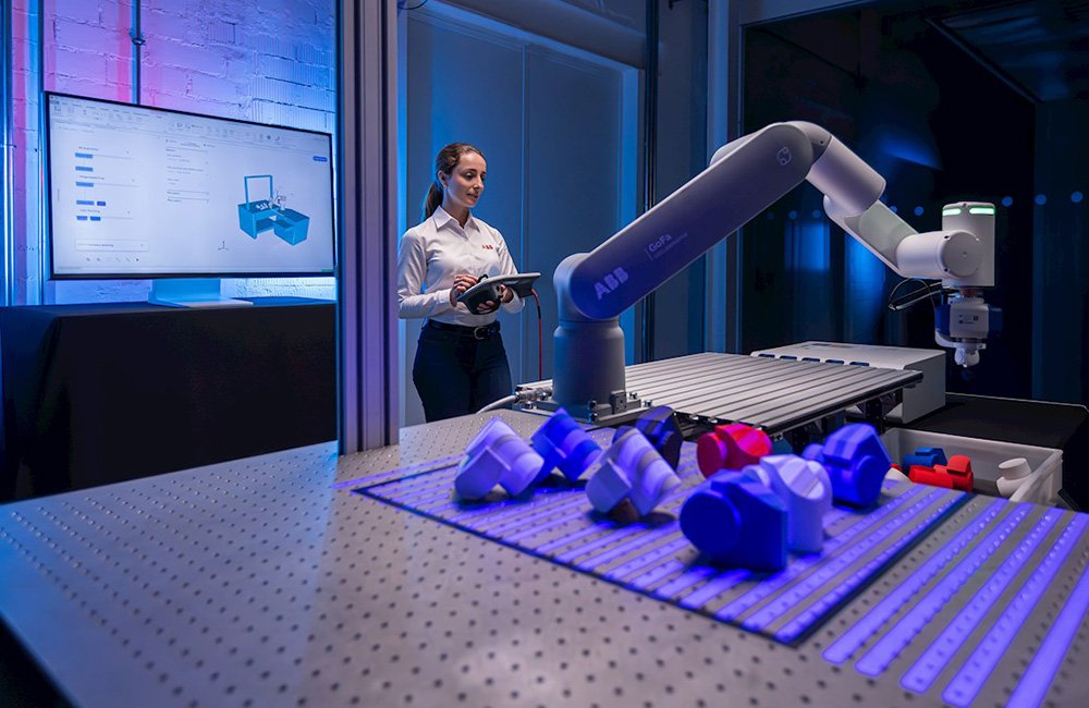 A woman with a tablet controlling an ABB cobot. OmniCore EyeMotion is intended to make industrial automation faster to deploy.